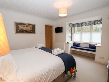 A bedroom with a bed, folded towels, wall-mounted TV, and a window seat at Mellows Thorpeness in Thorpeness