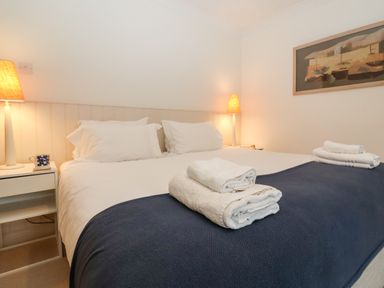 A bedroom with a bed with white pillows and sheets and folded towels on top at Mellows Thorpeness in Thorpeness
