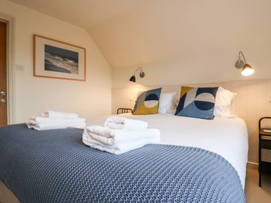 A bedroom with a bed covered by a blue knitted blanket and white towels at Mellows Thorpeness in Thorpeness