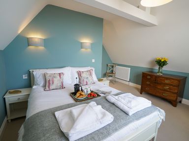 A bedroom with a double bed bedside tables a wooden dresser and a chair at Shingle Skies Aldeburgh