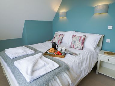 A bedroom with a made bed with white linens breakfast tray and towels at Shingle Skies Aldeburgh in Aldeburgh