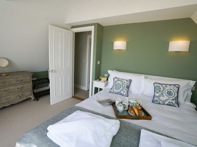 A bedroom with a bed with cushions and a tray with croissants and tea at Shingle Skies Aldeburgh