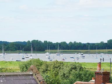 A view of boats on water with trees and rooftops in the foreground at Shingle Skies Aldeburgh