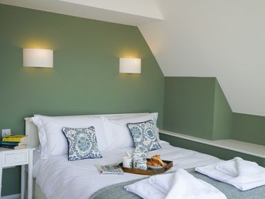 A bedroom with a bed with white bedding and decorative pillows and a tray with breakfast items on it at Shingle Skies Aldeburgh in Aldeburgh