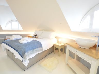 A bedroom with a bed with towels on a blanket bedside table with a lamp and a wash basin on a wooden table at The Round House in Easton near Framlingham