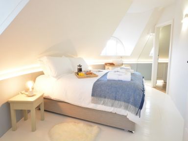A bedroom with a bed a bedside table lamp towels and a tray with breakfast at The Round House in Easton near Framlingham
