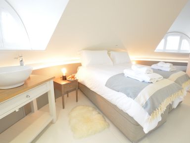 A bedroom with a bed towels bedside table lamp and a washbasin at The Round House in Easton near Framlingham