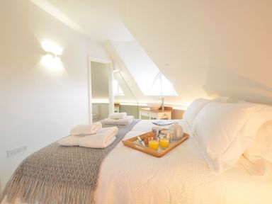 A bedroom with a made bed towels and a tray with breakfast items at The Round House in Easton near Framlingham