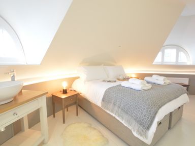 A bedroom with a bed and bedside tables under slanted ceilings at The Round House in Easton near Framlingham