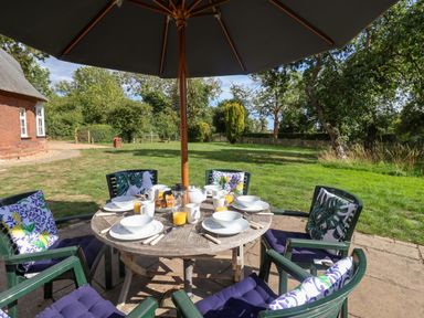 A dining table set with plates and drinks in the garden at The Round House in Easton near Framlingham