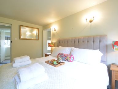 A bedroom with a large bed and towels on it and a mirror on the wall at Church Farm Cottage Dunwich Near Westleton