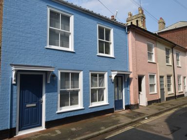 A street with terraced houses painted blue pink and cream with windows and front doors at 51 Tern Cottage Aldeburgh