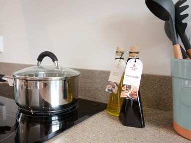 A kitchen counter with a stainless steel pot on a stove and bottles of white truffle olive oil and fig and date balsamic cream vinegar at 51 Tern Cottage Aldeburgh