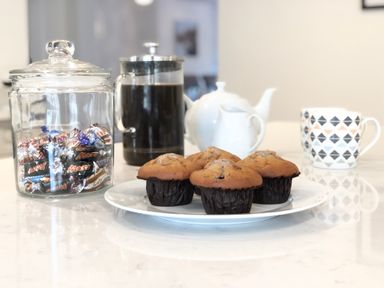 A kitchen counter with muffins on a plate a glass jar of candy a coffee press a white teapot a milk jug and a patterned mug at Bedingfield House nr Debenham Debenham