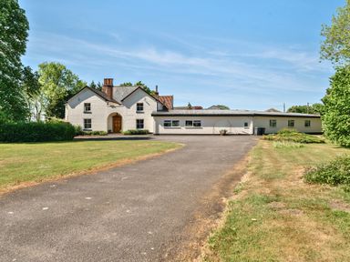 A white house with a wooden door and multiple windows surrounded by grass and trees at Bedingfield House nr Debenham Debenham