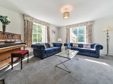 A living room with two blue sofas a glass coffee table and an upright piano at Bedingfield House nr Debenham Debenham