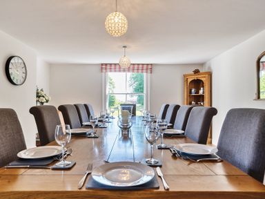 A dining room with a long wooden table set with plates glasses and cutlery at Bedingfield House nr Debenham Debenham
