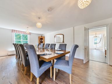 A dining room with a wooden table set with plates and glasses and grey chairs at Bedingfield House nr Debenham in Debenham