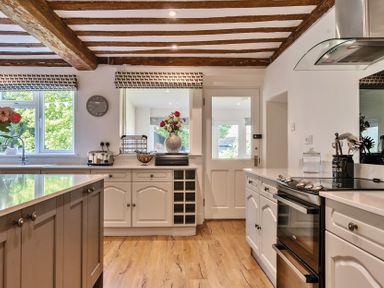 A kitchen with wooden ceiling beams a white door and cabinets and kitchen utensils at Bedingfield House nr Debenham in Debenham