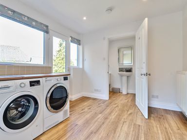 A laundry room with washing machine, dryer, sink, and wooden floor at Bedingfield House nr Debenham in Debenham