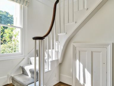 A staircase with carpeted steps and a wooden handrail next to a window and a small door under the stairs at Bedingfield House nr Debenham Debenham