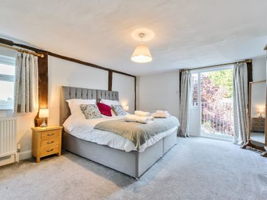 A bedroom with a large bed bedside tables lamps a standing mirror and a door leading outside at Bedingfield House nr Debenham in Debenham