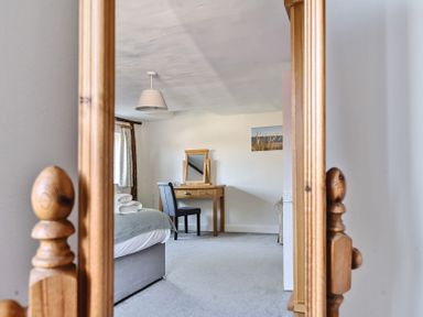 A bedroom reflected in a wooden mirror with a bed towels on a bed and a dressing table with a chair at Bedingfield House nr Debenham Debenham