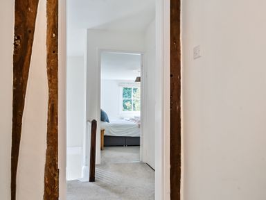 A hallway leading to a bedroom with a bed and window at Bedingfield House nr Debenham