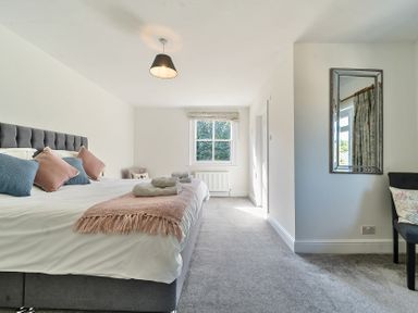 A bedroom with a bed with pillows and folded towels a window a mirror and a chair at Bedingfield House nr Debenham in Debenham