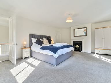 A bedroom with a double bed bedside tables wardrobe and fireplace at Bedingfield House nr Debenham
