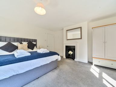 A bedroom with a bed, fireplace with a mirror, wardrobe and a lamp at Bedingfield House, nr Debenham in Debenham