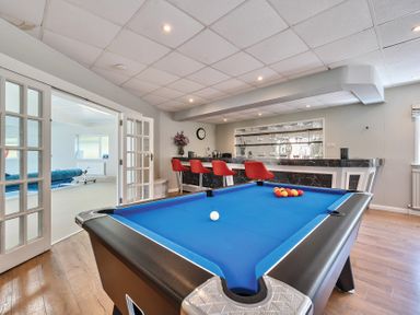 A games room with a pool table and a bar with red stools at Bedingfield House nr Debenham