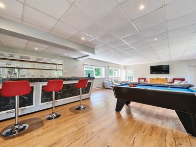 A games room with a pool table red bar stools a bar area sofas and a wall mounted television at Bedingfield House nr Debenham Debenham