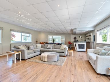 A living room with two sofas a round ottoman and a bar area with stools at Bedingfield House nr Debenham Debenham 