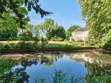 A house next to a pond with trees and grass at Bedingfield House nr Debenham Debenham