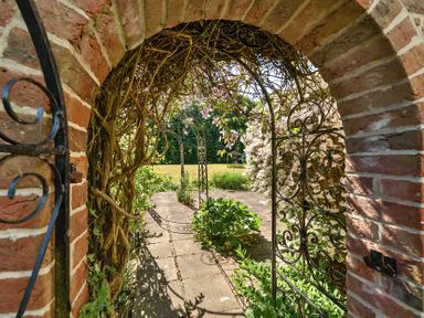 A garden path with metal archways and brick arch entrance at Bedingfield House nr Debenham Debenham 