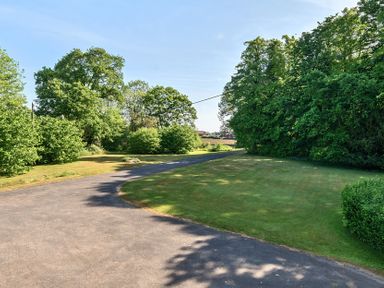 A paved driveway with grass lawns and trees on both sides at Bedingfield House nr Debenham Debenham