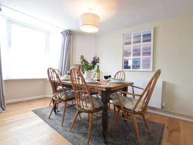 A dining room with wooden table and chairs set with bowls and glasses near a window at Seaflower Aldeburgh in Aldeburgh