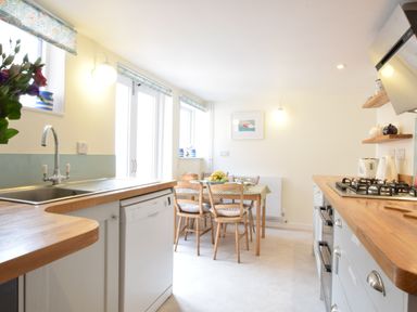 A kitchen with a dining table and chairs next to a window at Seaflower Aldeburgh