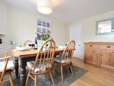 A dining room with a wooden table and chairs set with bowls glasses and wine at Seaflower Aldeburgh in Aldeburgh