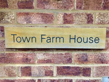 A wooden sign with Town Farm House on a brick wall at Town Farm House Orford