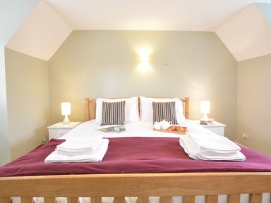 A bedroom with a wooden bed a white mattress and two bedside tables with lamps at Town Farm House Orford