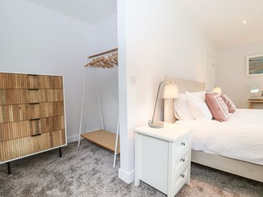 A bedroom with a bed bedside table with lamp chest of drawers and clothes rack at Town Farm House Orford