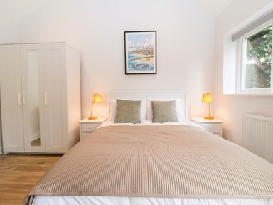 A bedroom with a double bed two bedside tables with lamps a wardrobe and a window at Town Farm House Orford