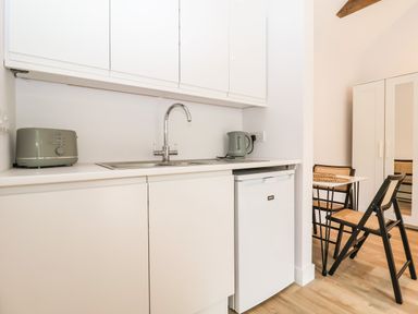 A kitchenette with a sink, toaster, kettle, small fridge, dining table, and chairs at Town Farm House Orford