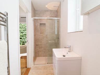 A bathroom with a glass shower enclosure a white sink and a towel rack at Town Farm House Orford