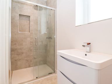 A bathroom with a glass shower enclosure and a white sink with a faucet at Town Farm House Orford