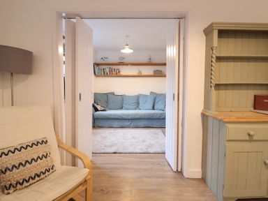 A living room with a sofa and bookshelf at Corner Cottage, Thorpeness