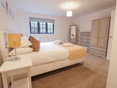 A bedroom with a double bed and furniture at Corner Cottage, Thorpeness