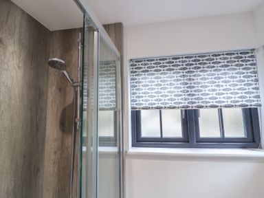 A bathroom with a shower and window at Corner Cottage, Thorpeness